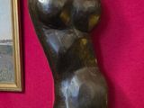 une statue représentant une femme assise sur un tabouret à côté d'un tableau