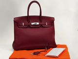 un sac à main en cuir rouge posé sur un tissu orange