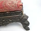 un petit tabouret surmonté d'un coussin rouge