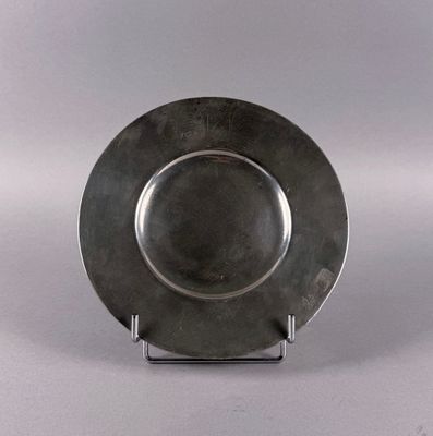 a silver plate on a stand on a white surface