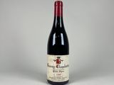une bouteille de vin rouge posée sur une table blanche