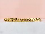 un gros plan d'un bracelet en or posé sur une surface en marbre