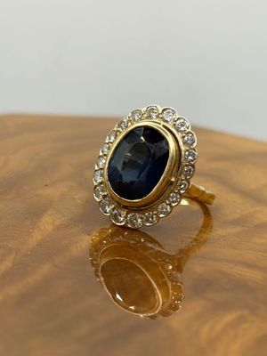 a close up of a gold ring with a blue stone surrounded by diamonds