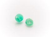 a pair of green glass beads sitting on top of a white surface