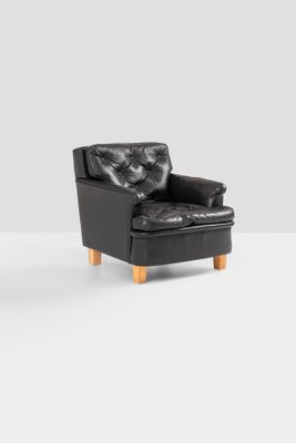 pair of black leather lounge chairs with wooden legs