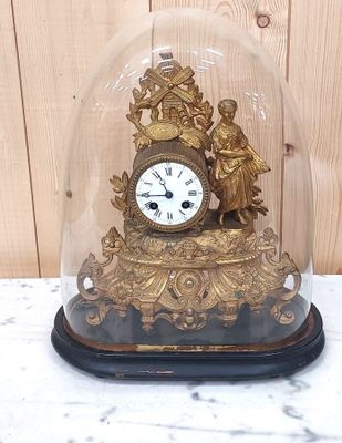 une horloge en or sous un dôme de verre sur une table