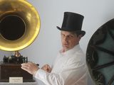 a man in a top hat standing in front of a gramphone