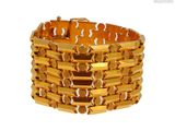 une image d'un gros plan d'un bracelet en or sur un fond blanc