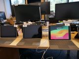trois ordinateurs portables posés sur un bureau devant un écran d'ordinateur