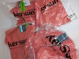 trois t-shirts roses sont emballés dans des sacs en plastique sur une table