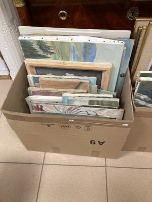 une boîte en carton remplie de tableaux et de photos, posée par terre