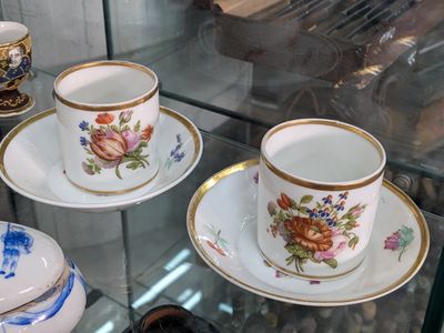 many cups and saucers on display in a glass case