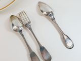 two silver spoons and a fork on a white table