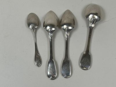 quatre cuillères et un repose-cuillère sur une surface blanche