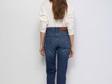 the back view of a woman standing in front of a white wall