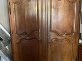 a wooden armoire in a room with a red rug