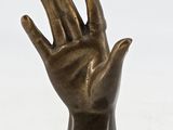 bronze statue of a hand on a pedestal on a white background