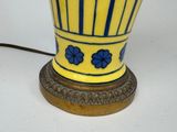 a yellow vase with blue flowers on it sitting on a table