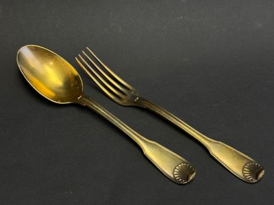 two gold spoons and a fork on a black surface