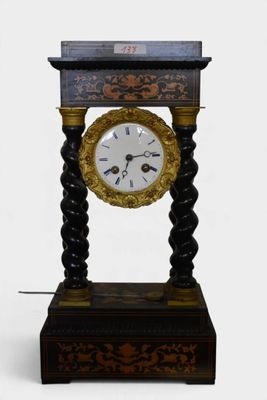 a black and gold clock on a stand on a white background