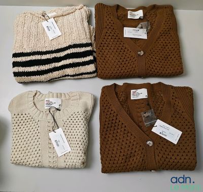 three pairs of sweaters are on a table with tags on them