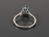 an emerald and diamond ring on a black surface