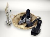 un panier sur lequel est posée une paire de chaussures, à côté d'un vase rempli de fleurs