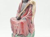 figurine of a woman sitting on a rock with a harp