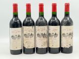 quatre bouteilles de vin sont alignées sur une surface blanche