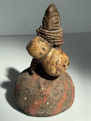 une petite statue représentant un homme assis sur un rocher
