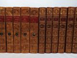 six old books are lined up in a row on a white surface