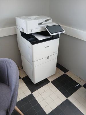 une imprimante blanche posée sur un sol à damier noir et blanc