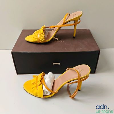 une paire de sandales à talons hauts jaunes posée sur une boîte
