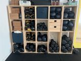 une étagère sur laquelle sont posés plusieurs kettlebells noirs