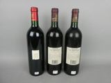 three bottles of red wine are lined up on a table