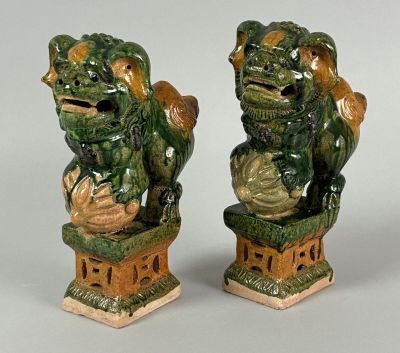 pair of green glazed foo foo foo statues on pedestals on grey background