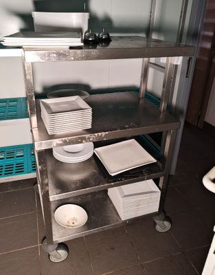 a metal cart with plates and bowls on it in a kitchen