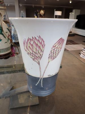un vase posé sur une table en verre, avec un autre vase à l'arrière-plan