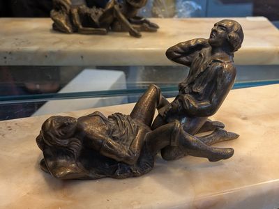 une statue en bronze représentant un homme et une femme assis sur un banc