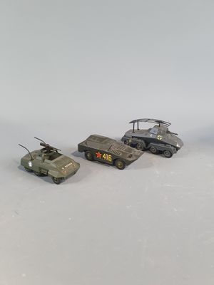 three toy army vehicles are lined up in a row on a white surface