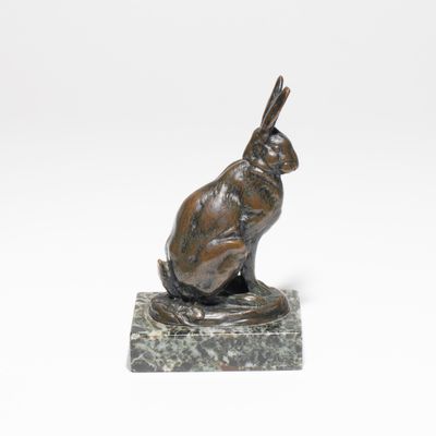 une statue en bronze représentant un lapin assis sur un socle en marbre
