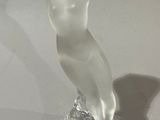 a glass figurine of a woman sitting on a table