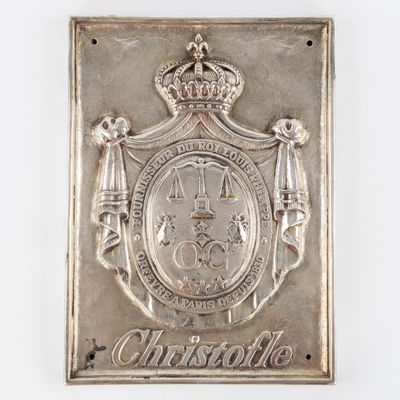 une vieille plaque en argent sur laquelle figurent une couronne et des armoiries