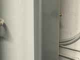 a water heater in the corner of a room next to a toilet