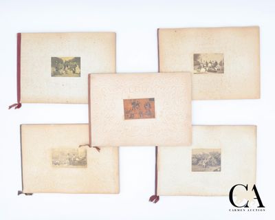 Plusieurs livres anciens sont disposés sur une surface blanche, avec un ruban rouge