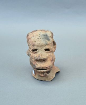 une sculpture en argile représentant le visage d'un homme sur une surface grise
