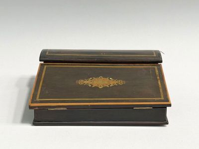 une vieille boîte noire et dorée posée sur une table blanche