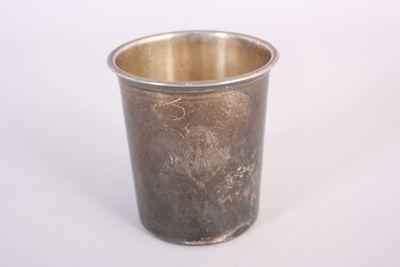 une tasse en argent posée sur une surface blanche