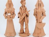 three clay figurines of a woman and a man holding a basket
