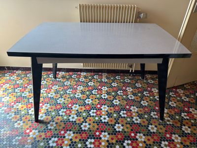 une table noire avec un plateau blanc posée sur un sol coloré